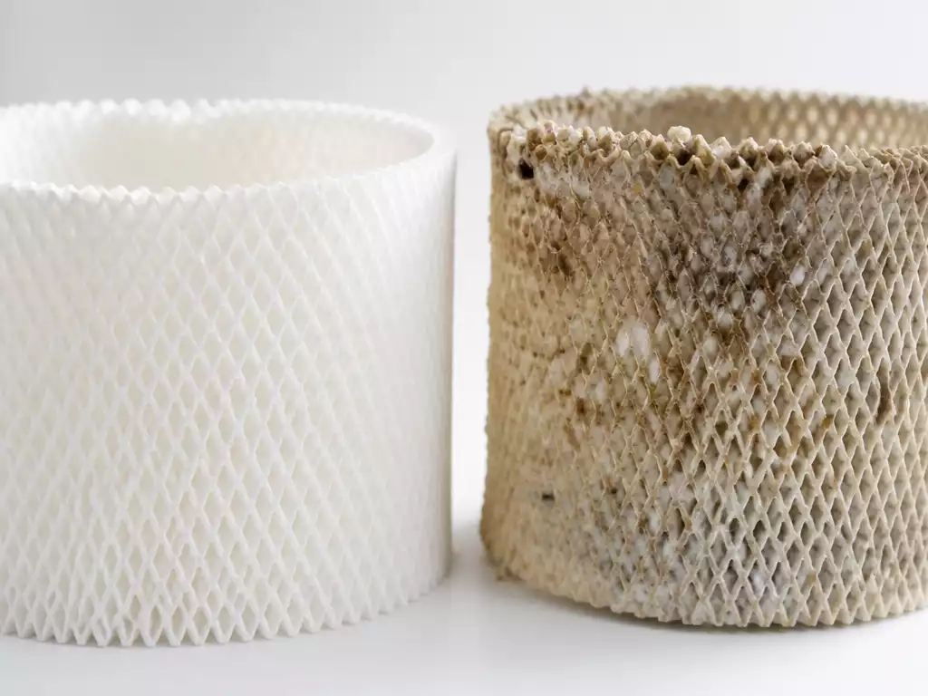 Close-up of a clean humidifier wick next to a dirty, discolored one, illustrating the difference in maintenance