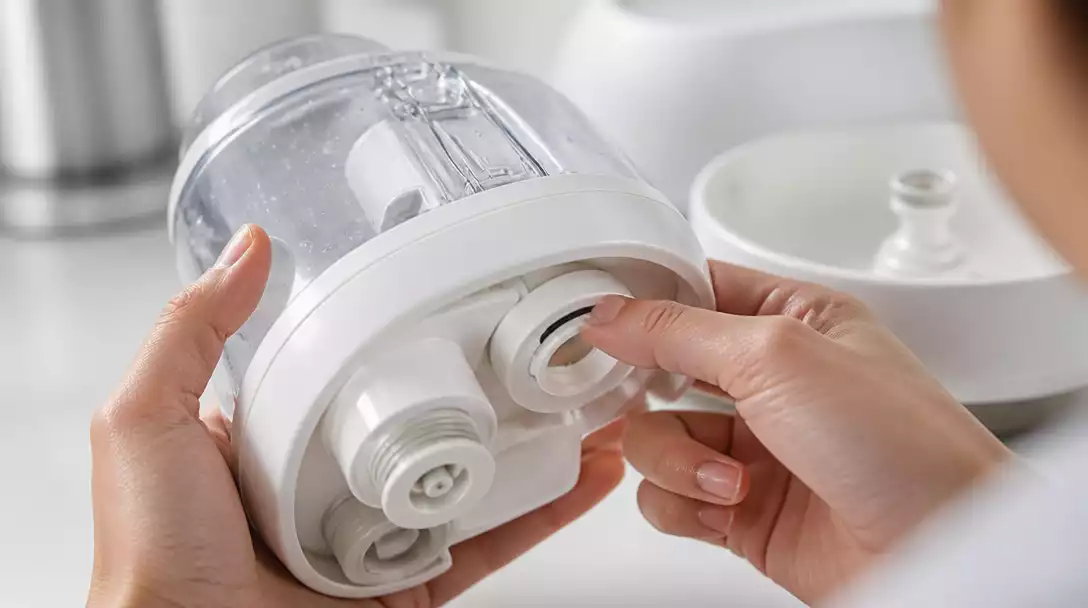 Person inspecting a humidifier for water leakage, checking seals and connections carefully